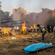 A man prepares a funeral pyre to cremate the body of a person, who died due to the coronavirus disease (COVID-19), at a crematorium ground in New Delhi